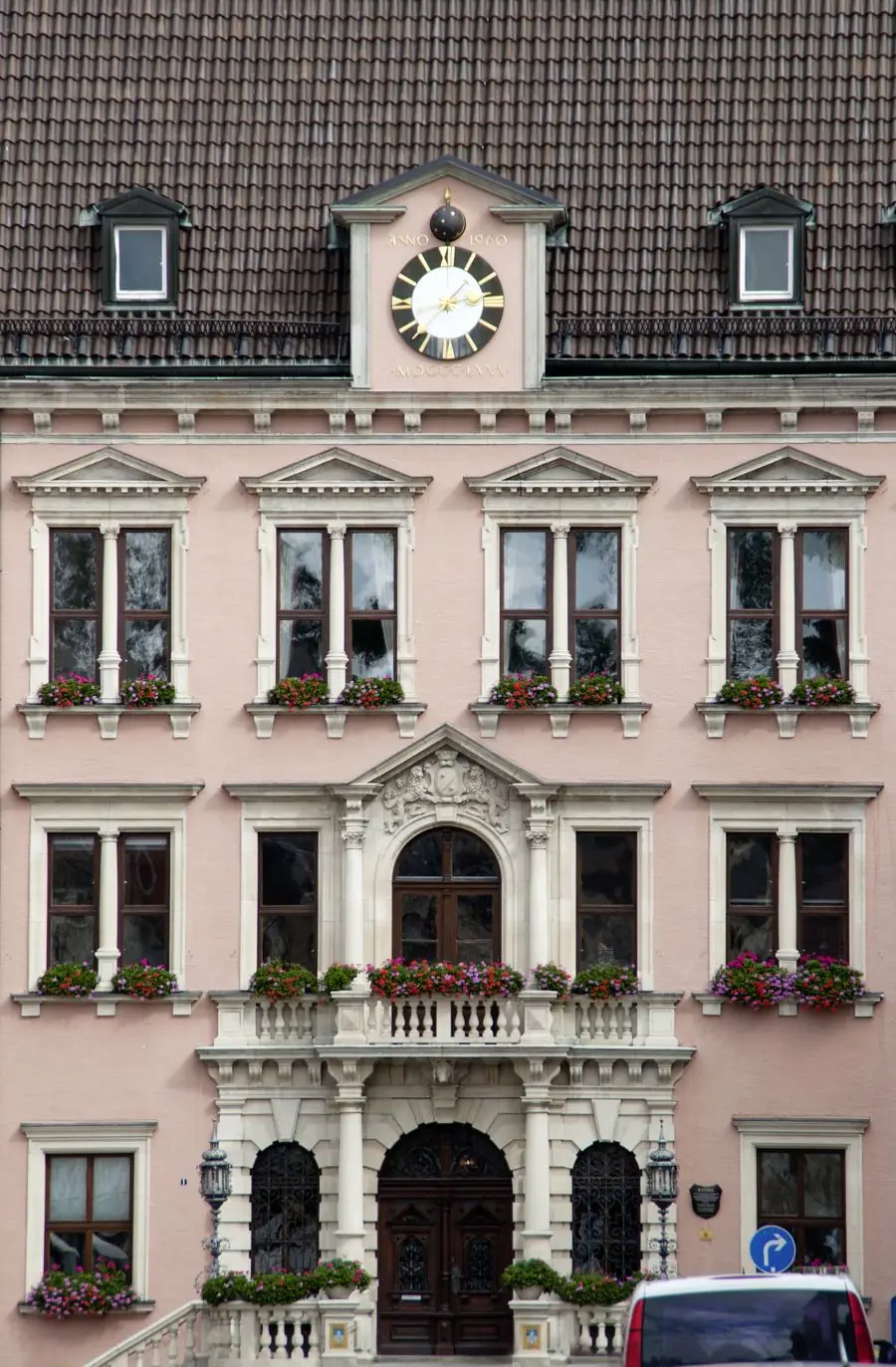 Historisches Rathausgebäude mit rosafarbener Fassade und Blumenschmuck an den Fenstern
